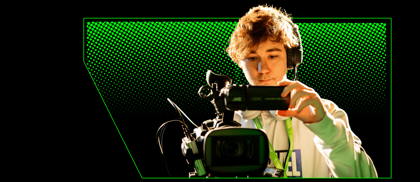 A film and tv student holding a professional camera wearing headphones and recording a video