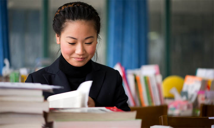 A foreign language student in front of a pile of books